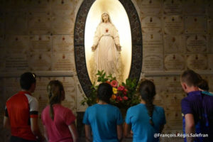 Photo or our young cyclists on Day 16 praying at a chapel under the watchful eyes of the Virgin.