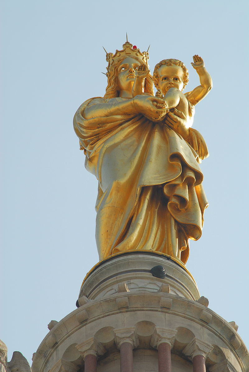 Photo of the 30' statue of the Madonna high atop the Basilica. Baby Jesus is in her arms and though she is looking far out to the sea, he is looking down and waving to those at the Basilica.