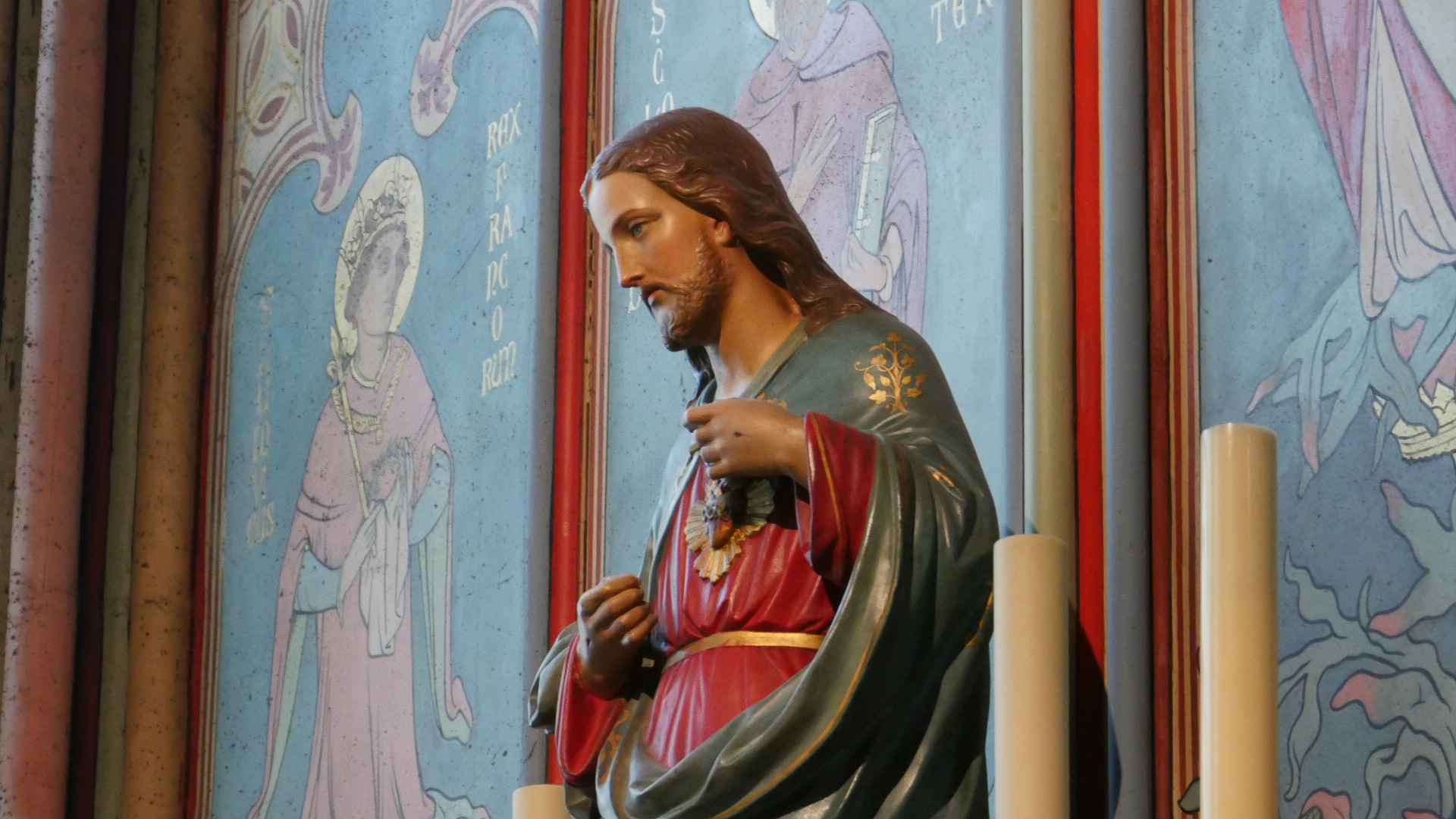 Photo of a close up of a beautiful red themed statue of Jesus in a section of the interior of Notre-Dame