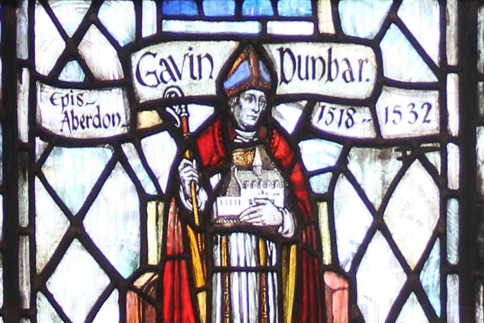 Photo of a stain glass window that shows Gavin Dunbar holding a copy of his beloved St. Mary's Hospital