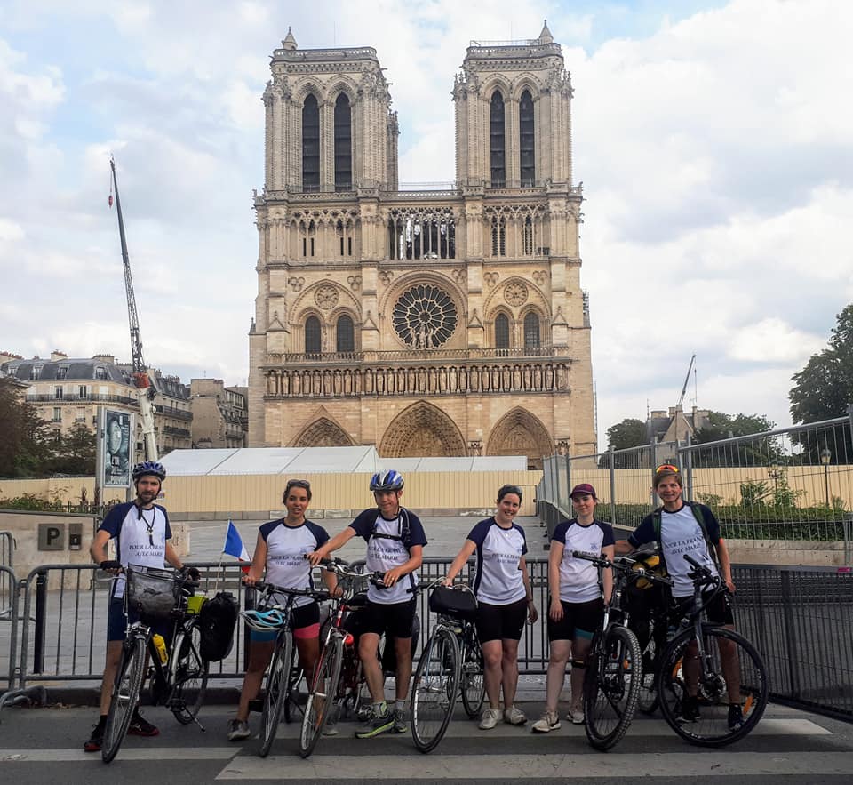 photo of The 2019 Grand Love of Mary cyclists arrive and pause in front of Notre Dame in Paris...