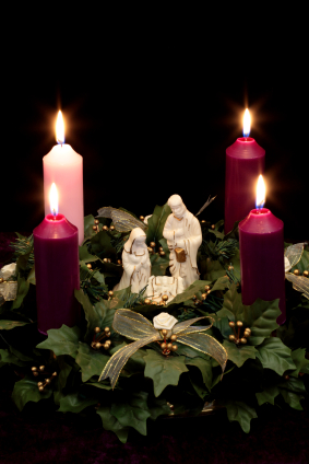 Photo of 4 lit advent candles and statue of the Madonna, Joseph and baby Jesus in the manger