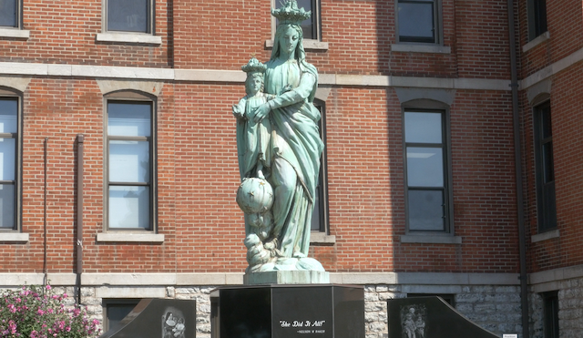 Photo of a statue in park across street from OLV Basilica of Mary with Jesus and words "She Did It All" on base