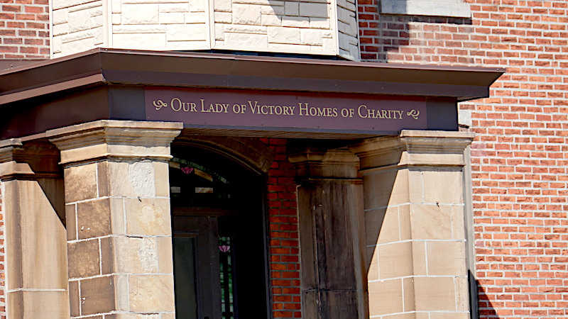 Photo of a campus building entrance with sign Our Lady of Victory Homes of Charity