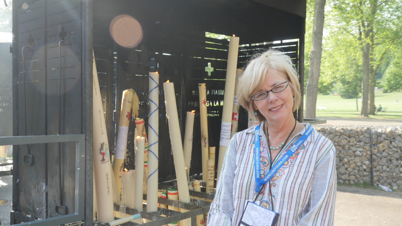 My wife, Rita (RIP 5/13/23) standing next to one of the many candle stands near the "Chapel of Light" at the Lourdes apparition site.