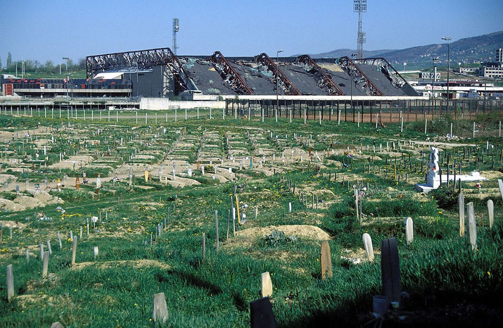 Bombed out ruins of 1984 winter Olympic Stadium in Sarajevo with tombstones from the Civil War in the foreground.