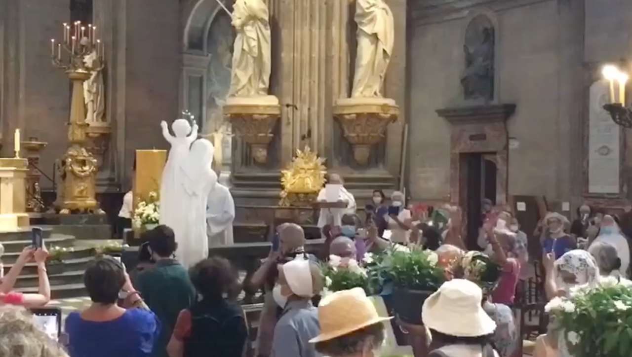 The Statue of 'Our Lady of the Great Return" is being marched up in an unknown church santurary with a crowd of marchers looking on during the "M de Marie" procession that took place while in Covid times in August 2021.