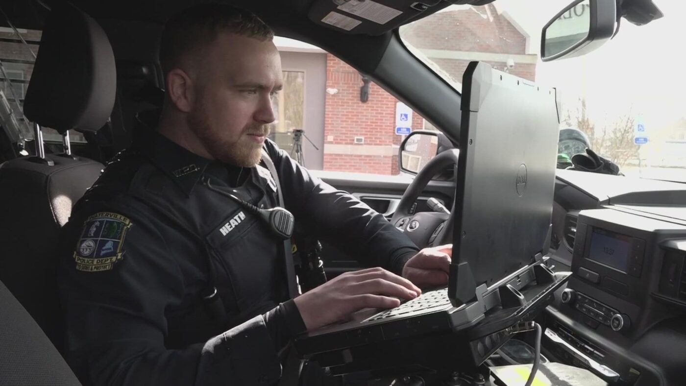 Photo of police officer in the driver's seat working on his laptop computer. Photo from University of Maine at Augusta.